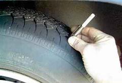 Checking tire tread depth.